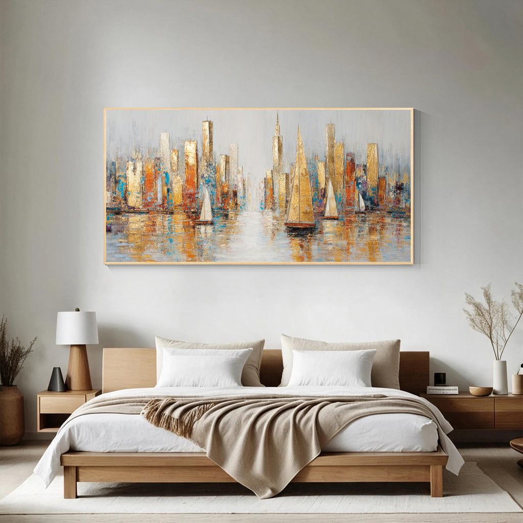 Abstract cityscape and sailboat wall art with gold frame displayed above a bed in a modern bedroom