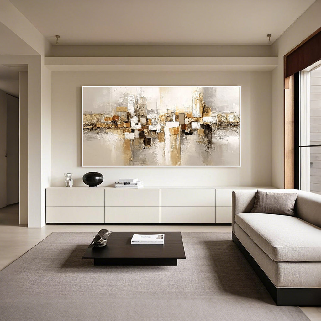 Beige gold geometric abstract wall art with white frame displayed in a modern living room, horizontal textured canvas painting with neutral tones and contemporary minimalist home decor