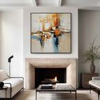 Beige orange and blue textured abstract wall art with black frame displayed above a fireplace, featuring layered brush strokes in a modern living room interior
