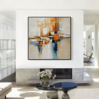 Beige orange and blue textured abstract wall art with black frame displayed above a fireplace in a modern living room, featuring layered brush strokes and contemporary decor