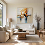 Beige orange and blue textured abstract wall art with gold frame displayed above a sofa in a modern living room, featuring layered brush strokes and contemporary home decor