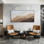 Black framed abstract textured wall art displayed in a modern minimalist interior with leather chairs, neutral brown and beige canvas artwork for contemporary home decor