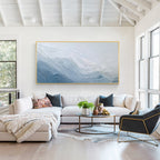 Blue and white textured abstract wall art painting displayed above a sofa in a bright modern living room