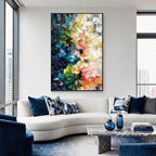 Colorful blue green pink and orange textured abstract wall art with black frame displayed above a sofa in a modern living room, featuring layered brush strokes and contemporary interior decor