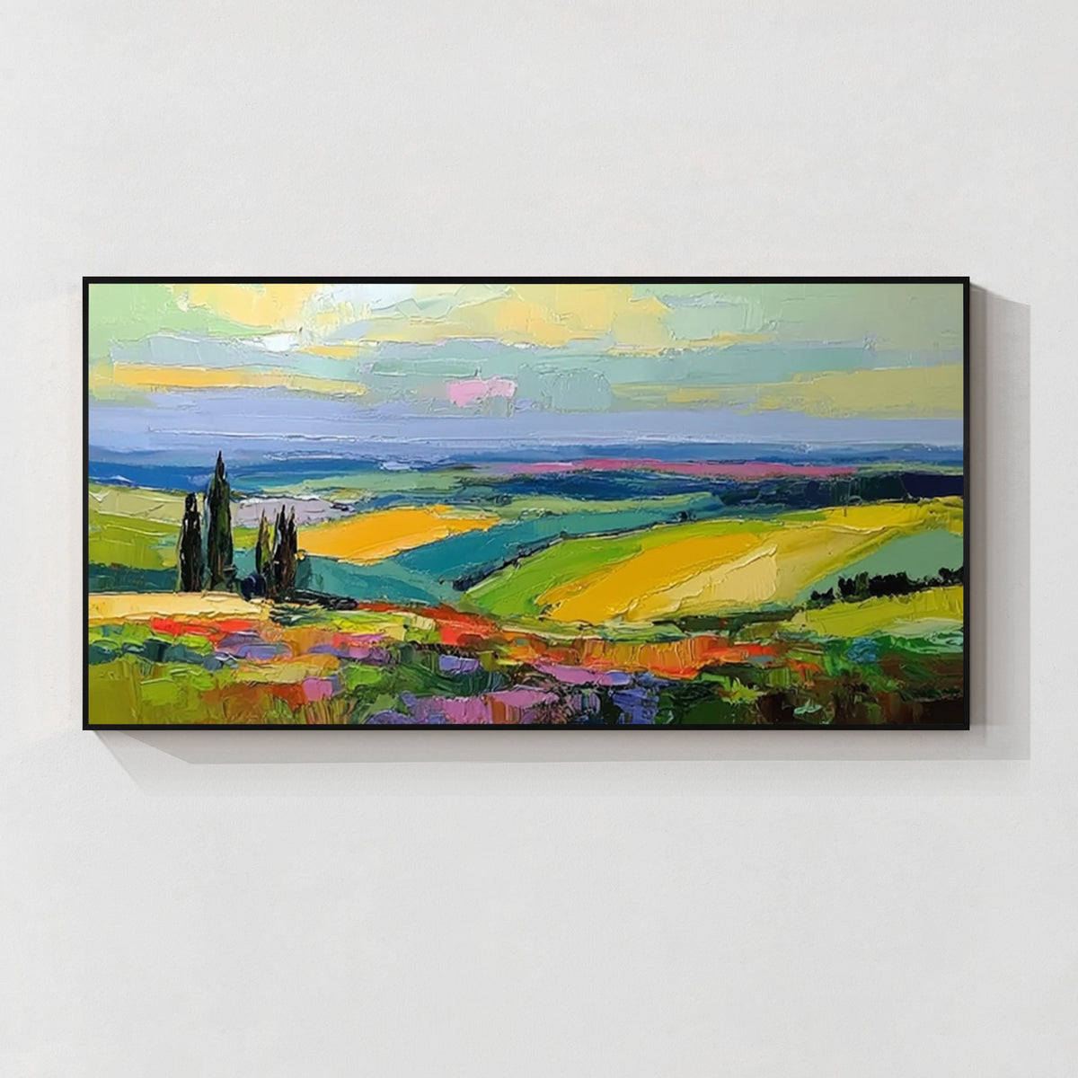 Colorful countryside landscape wall art with black frame featuring green fields, yellow hills and blue sky