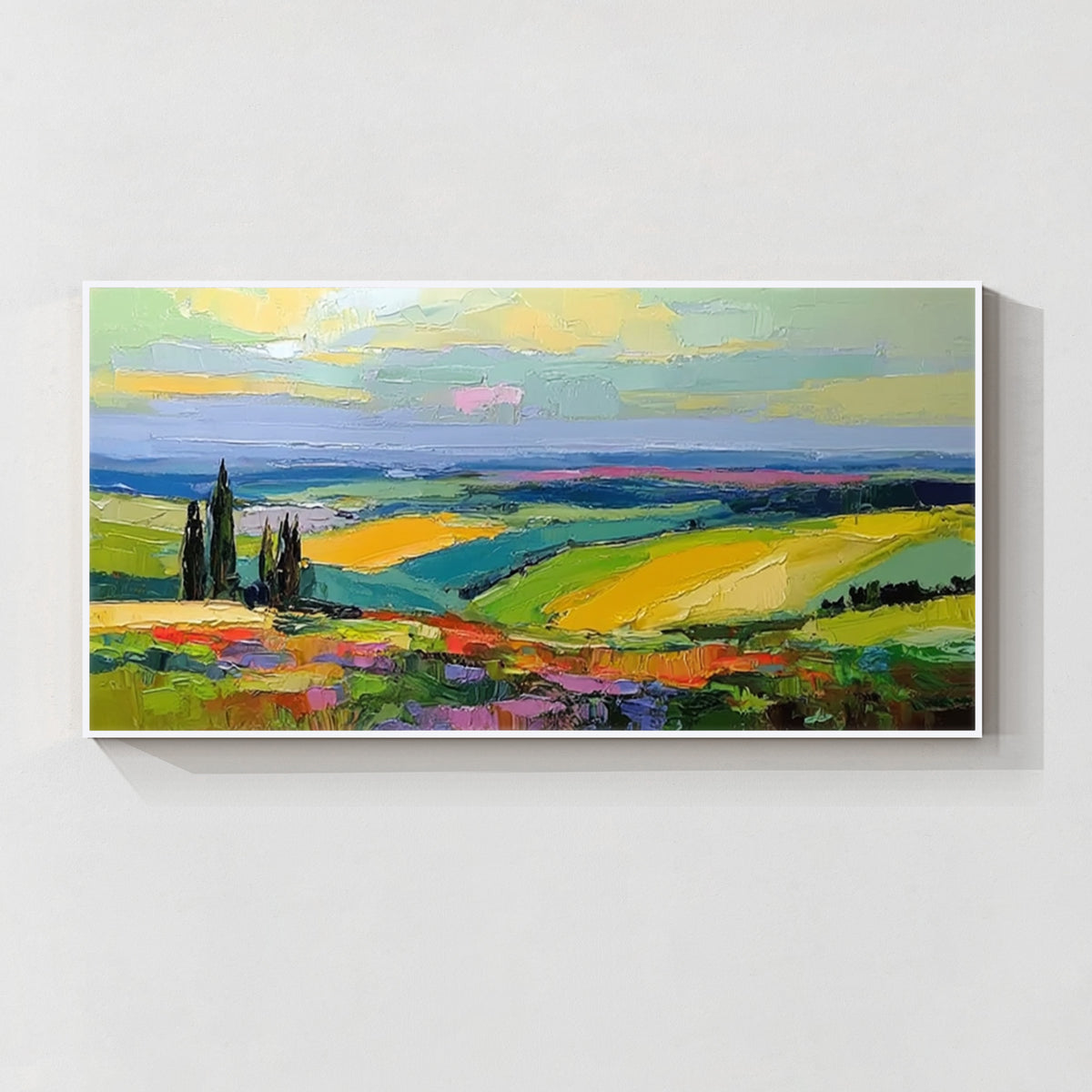 Colorful countryside landscape wall art with white frame featuring green fields, yellow hills and blue sky