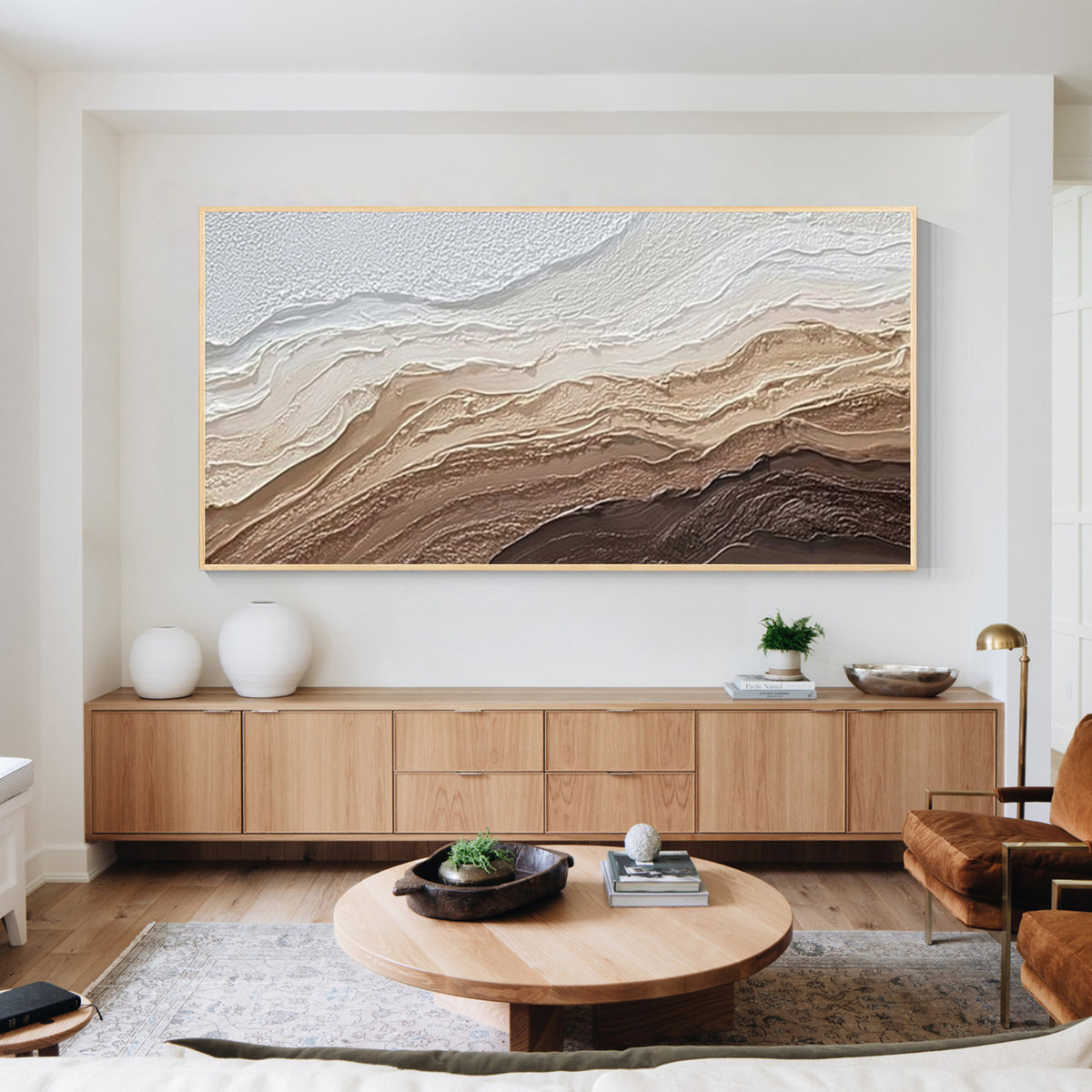 Modern abstract textured wall art with light wood frame displayed above a wooden cabinet in a minimalist living room, neutral beige and brown canvas artwork for home decor