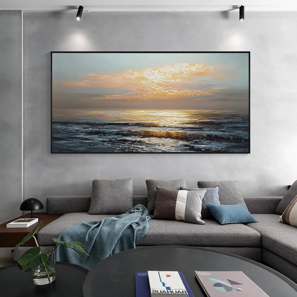 Sunset ocean wall art with black frame displayed above a sofa in a modern living room, featuring golden sunlight and textured ocean waves