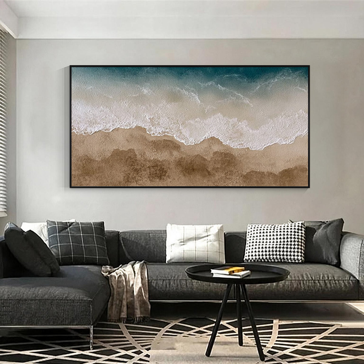 Textured ocean wave and beach wall art with black frame above a sectional sofa in a modern living room