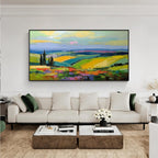Vibrant countryside landscape wall art with black frame displayed above a sofa in a modern living room
