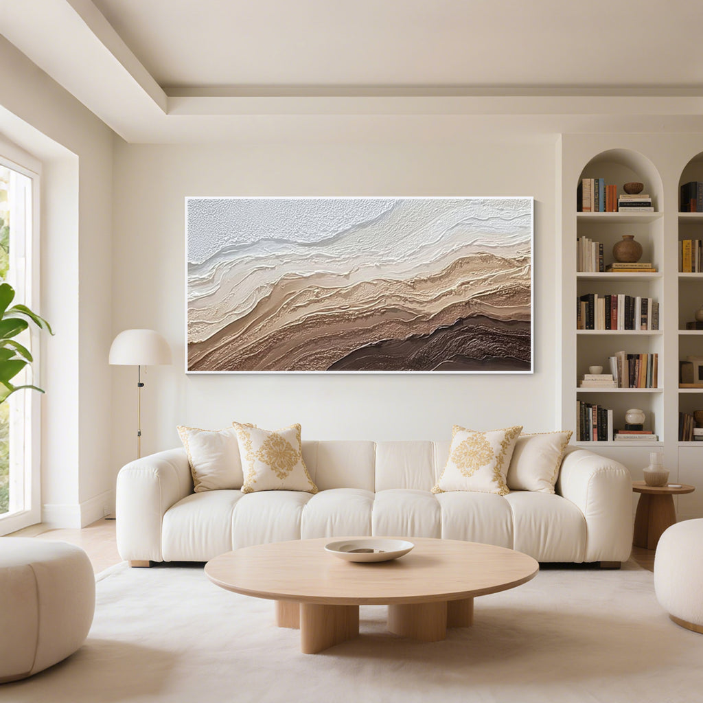 Modern abstract textured wall art with white frame displayed above a sofa in a minimalist living room, neutral beige and brown canvas artwork for contemporary home decor